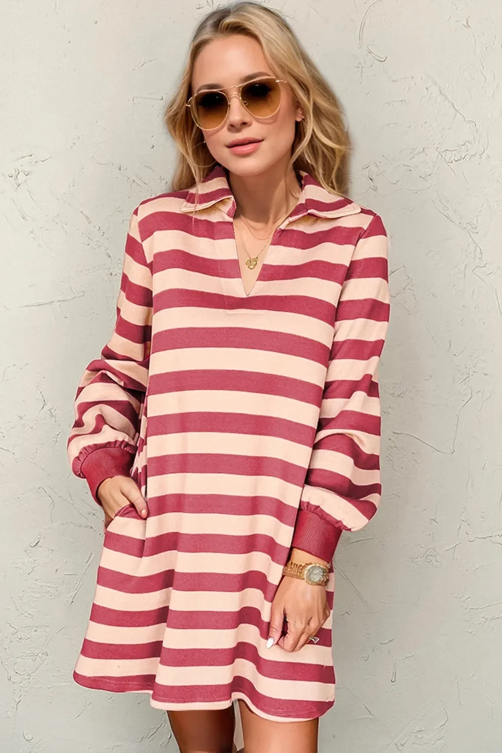 Woman in a deep rose and cream striped long-sleeve dress with a collared neckline, wearing sunglasses