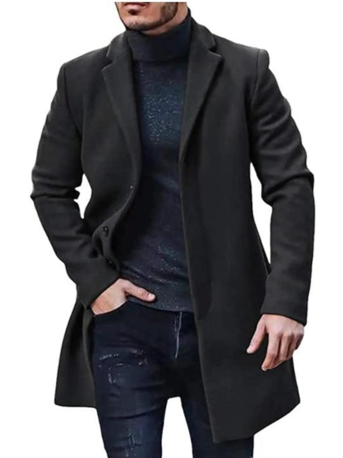 Man in a black knee-length overcoat over a dark turtleneck and dark jeans, one hand in his pocket
