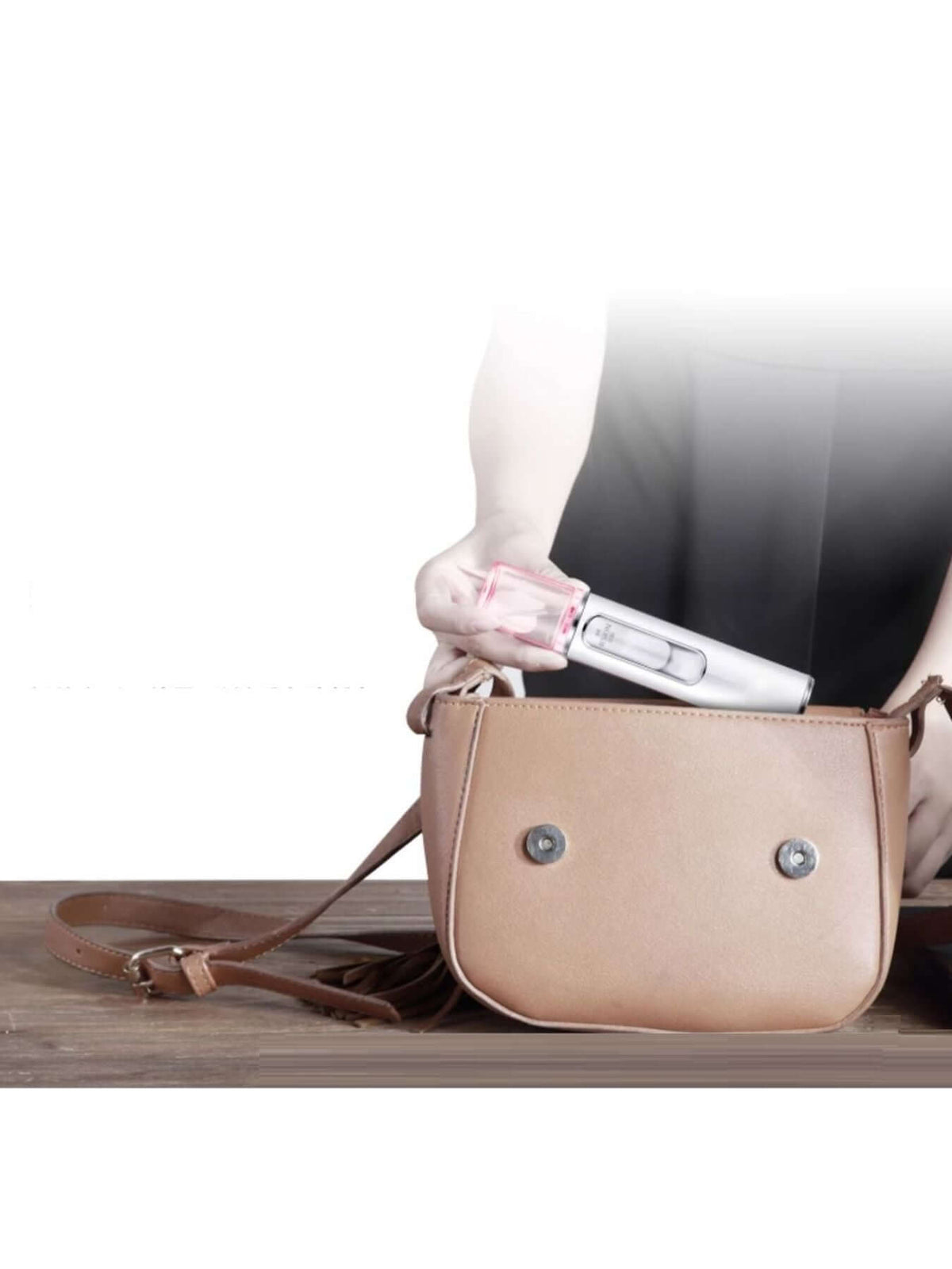 Hand holding a Portable Facial Mister Nano Sprayer while taking it out of a bag.