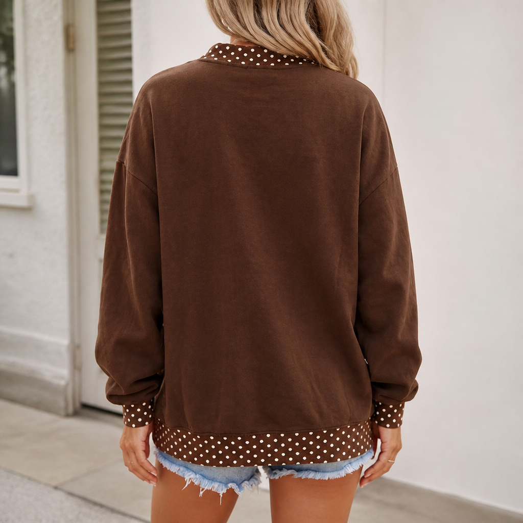 A woman shown from the back wearing a brown long-sleeve sweatshirt with white polka dot trim at the collar, cuffs, and hem, paired with denim shorts.